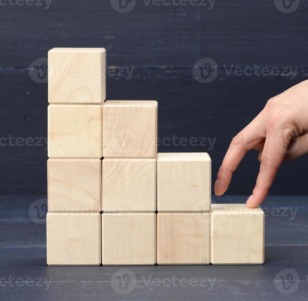 una pila de cubos de madera 6 los dedos de la persona suben los escalones. concepto de crecimiento empresarial, logro de objetivos, autoeducación foto