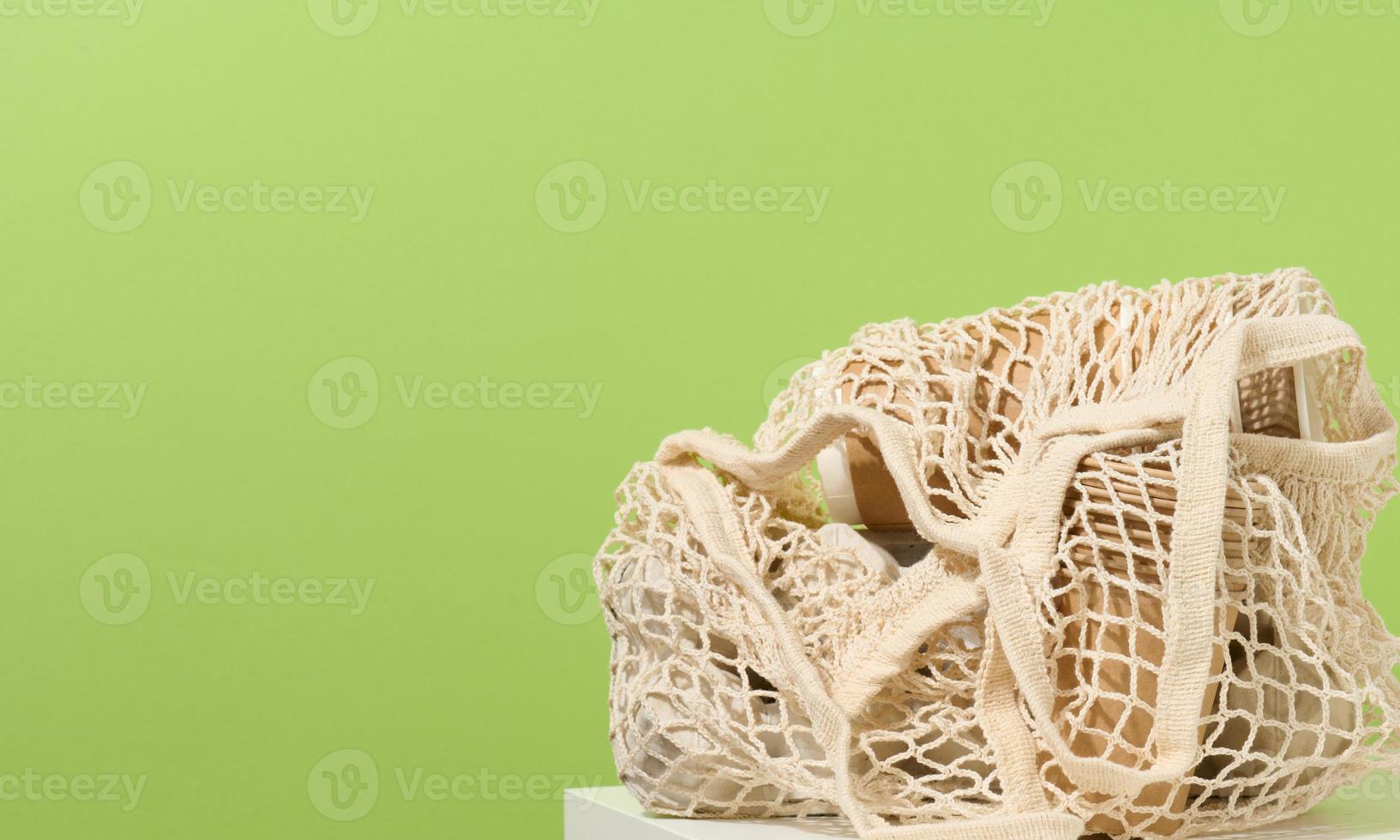 reusable white textile shopping bag with paper cups on a green background, zero waste photo