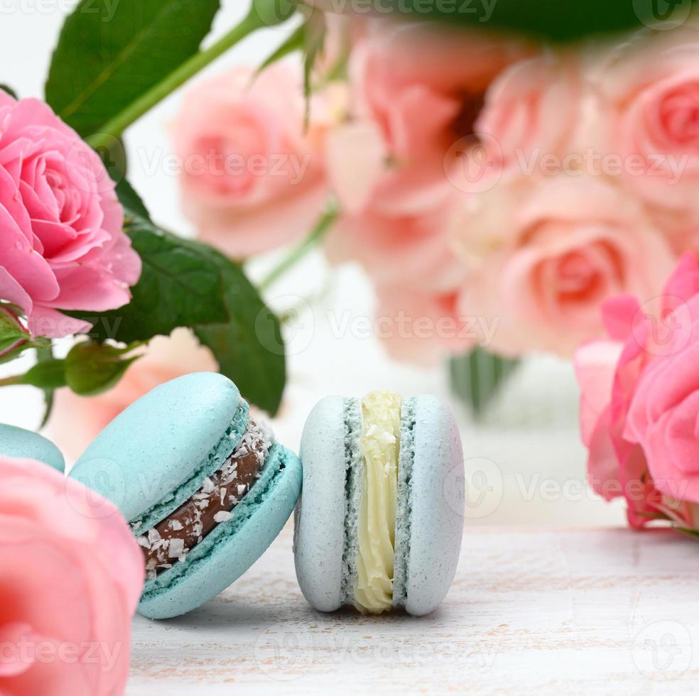 pila de macarons azules sobre una mesa blanca y capullos de rosa foto