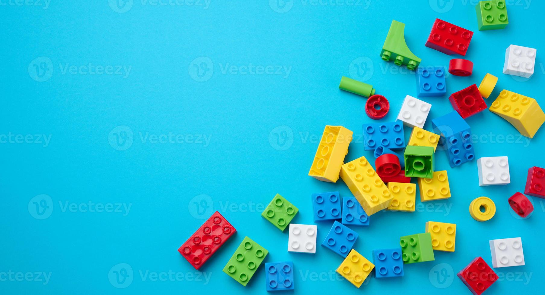 Scattered parts of a plastic children's designer, top view. Yellow blue background photo