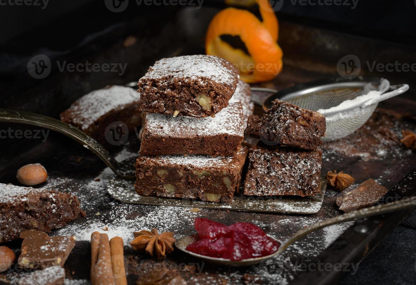 baked square pieces of chocolate brownie sprinkled with powdered sugar on the table photo