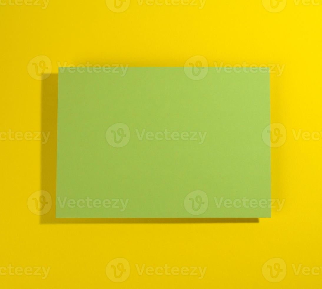 blank green sheet of paper on yellowe background with shadow photo