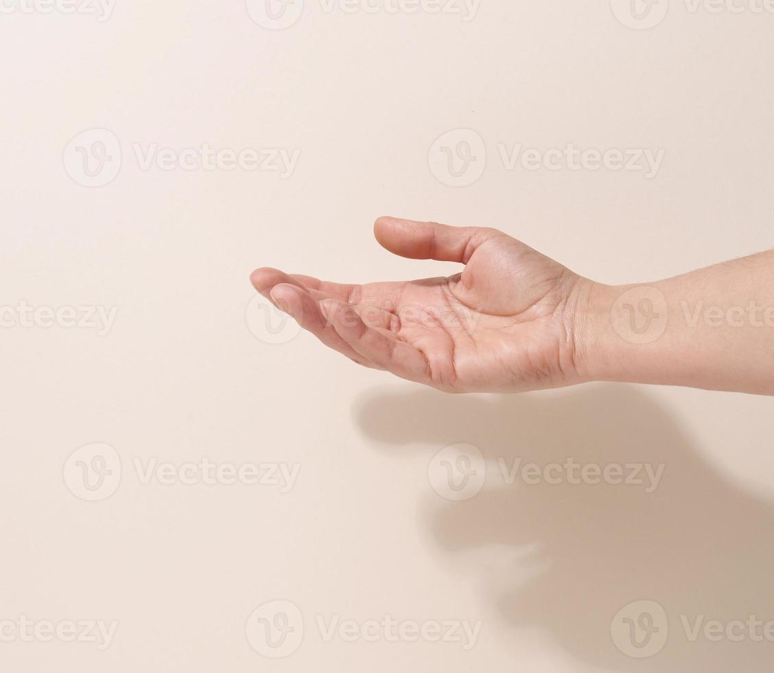 mano adolescente femenina para sostener algo sobre un fondo beige. publicidad y promoción de productos foto