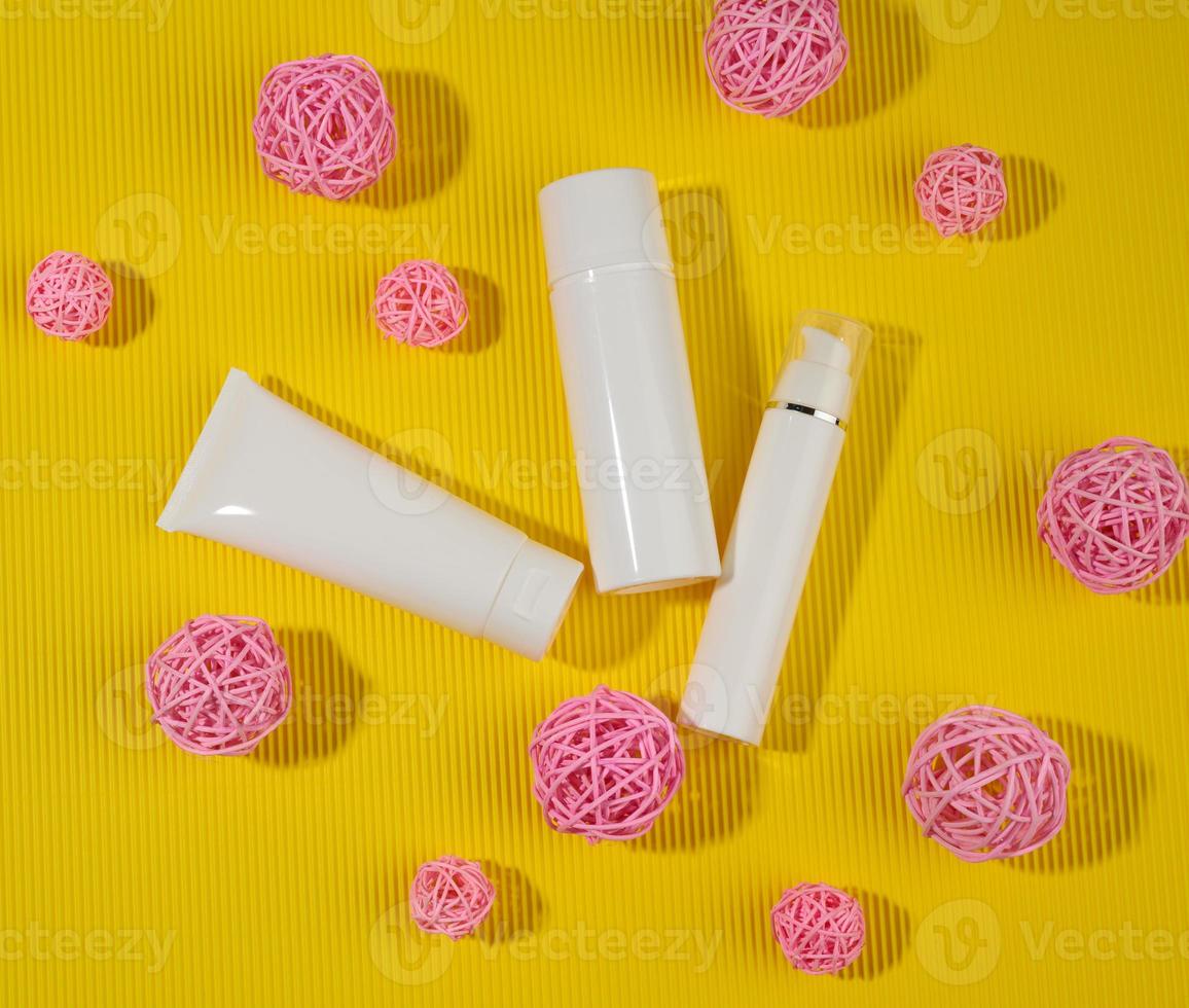 bottle and empty white plastic tubes for cosmetics on a yellow background. Packaging for cream, gel, serum, advertising and product promotion photo