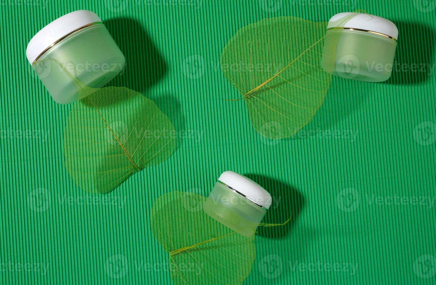 empty white jar for cosmetics on a green background. Packaging for cream, gel, serum, advertising and product promotion. Mock up, top view photo