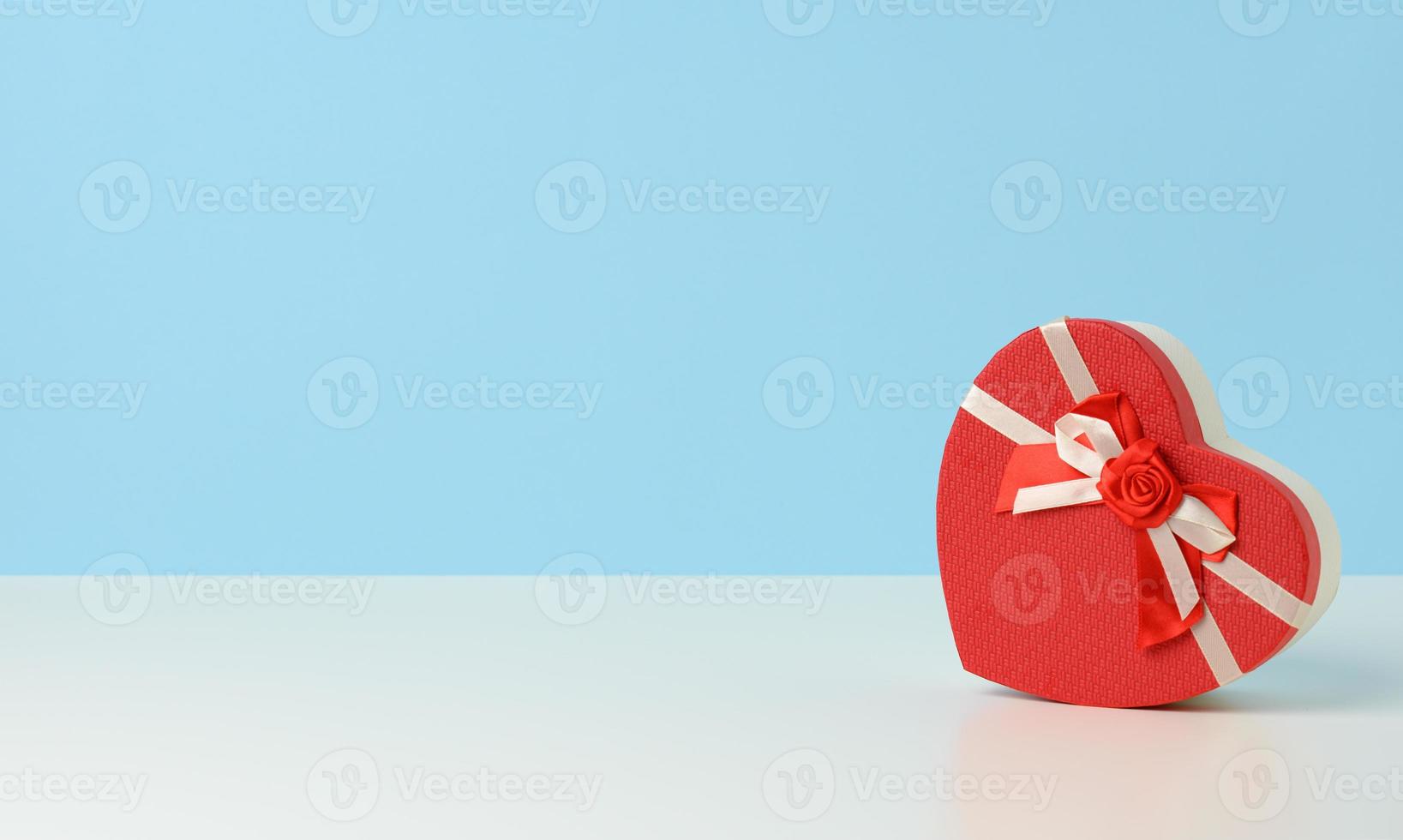 heart shaped red cardboard gift box on white table, festive backdrop photo