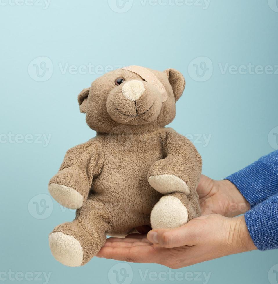 mano femenina sostenga un pequeño oso de peluche de juguete marrón foto