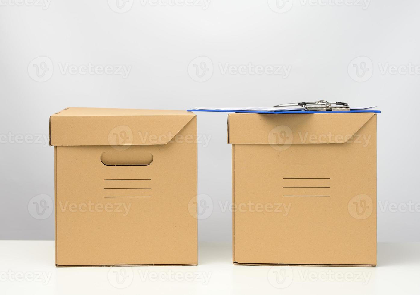 two cardboard boxes made of brown corrugated cardboard are on a white table, moving, goods delivery photo