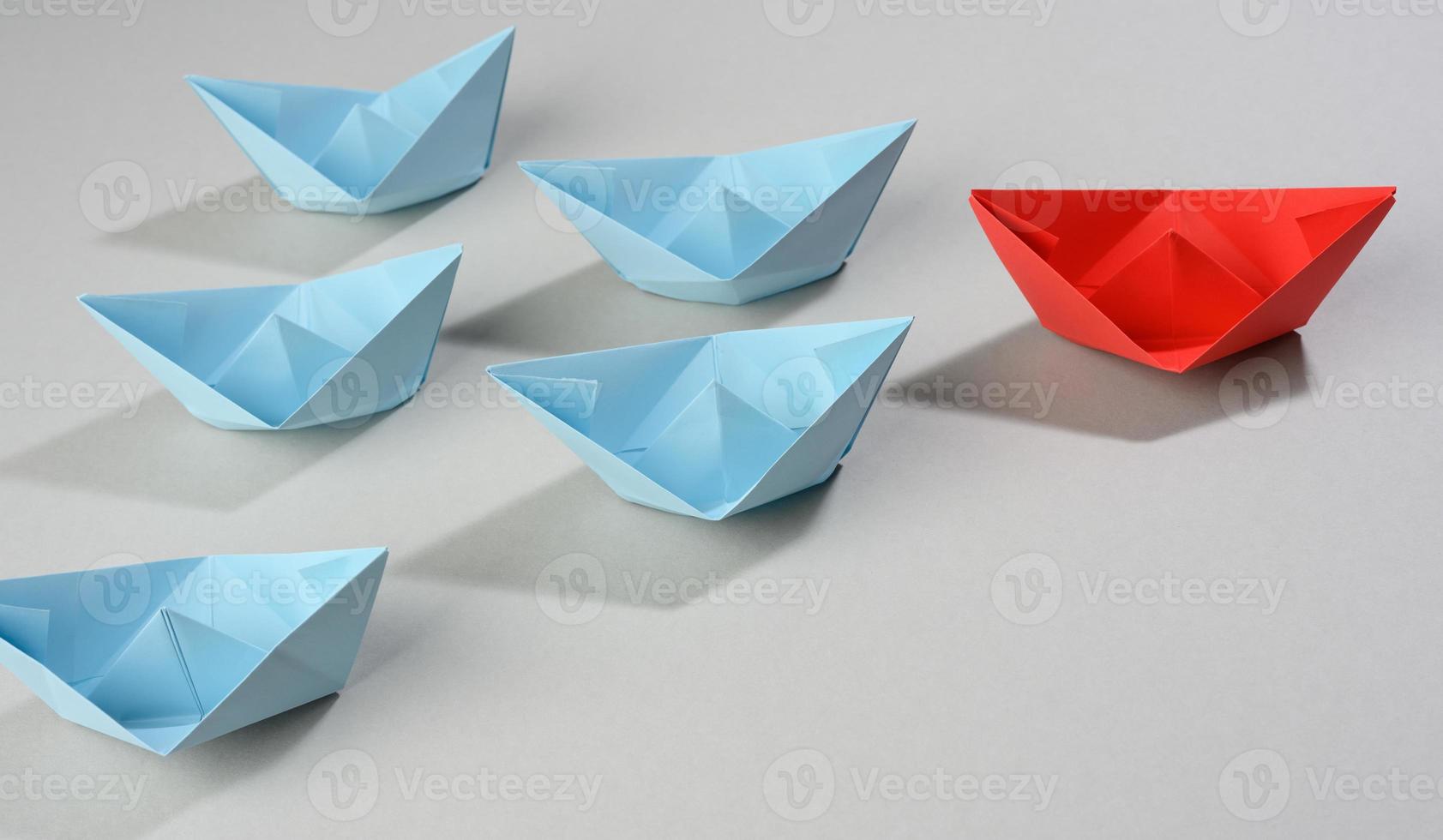 group of paper boats on a gray background. concept of a strong leader in a team, manipulation of the masses photo