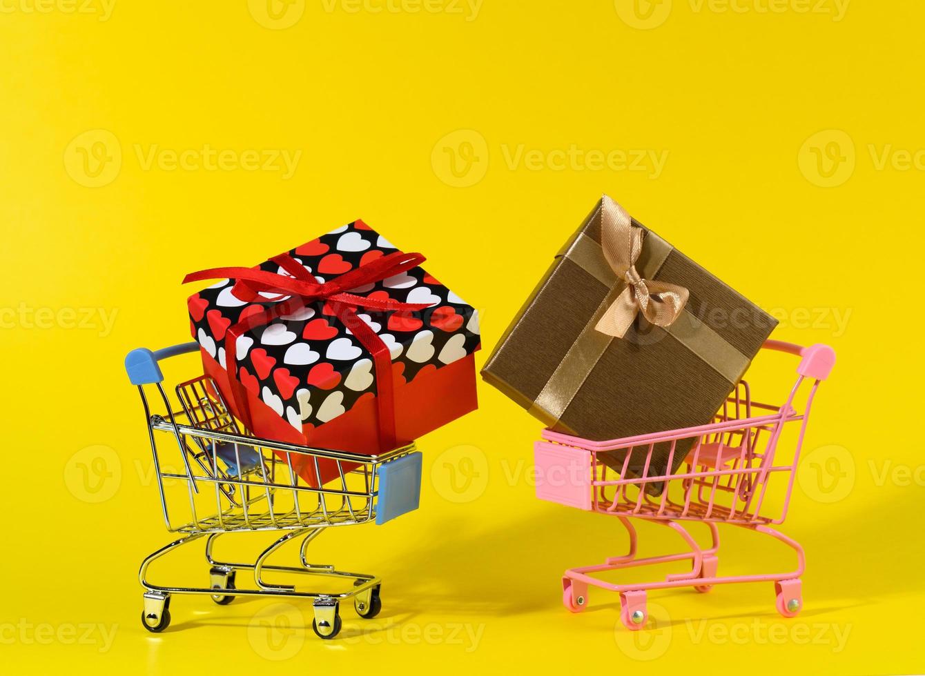 gift box with a red silk bow in a miniature metal trolley on a yellow background. Party Backdrop, surprise photo