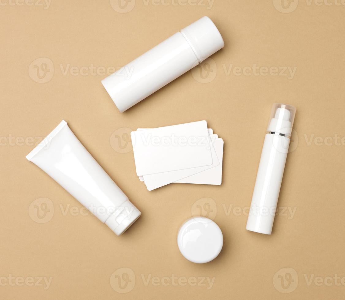 jar, bottle and empty white plastic tubes for cosmetics on a beige background. Packaging for cream, gel, serum, advertising and product promotion, mock up, top view photo
