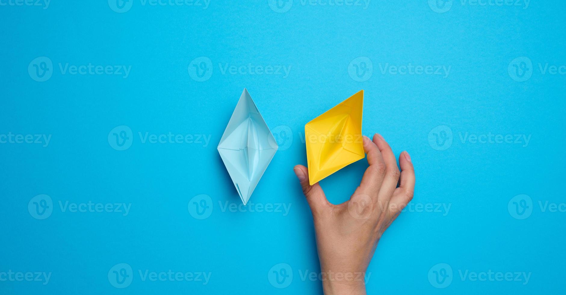 A woman's hand holds a yellow paper boat photo