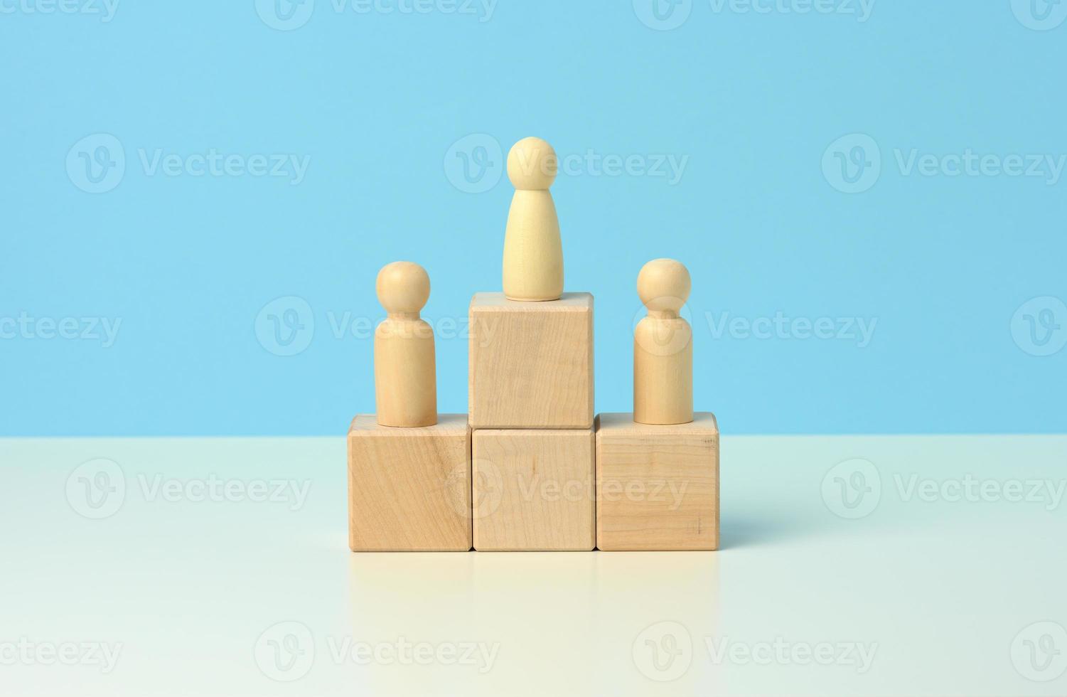 figuras de madera de hombres sobre un pedestal de sus cubos sobre un fondo azul foto