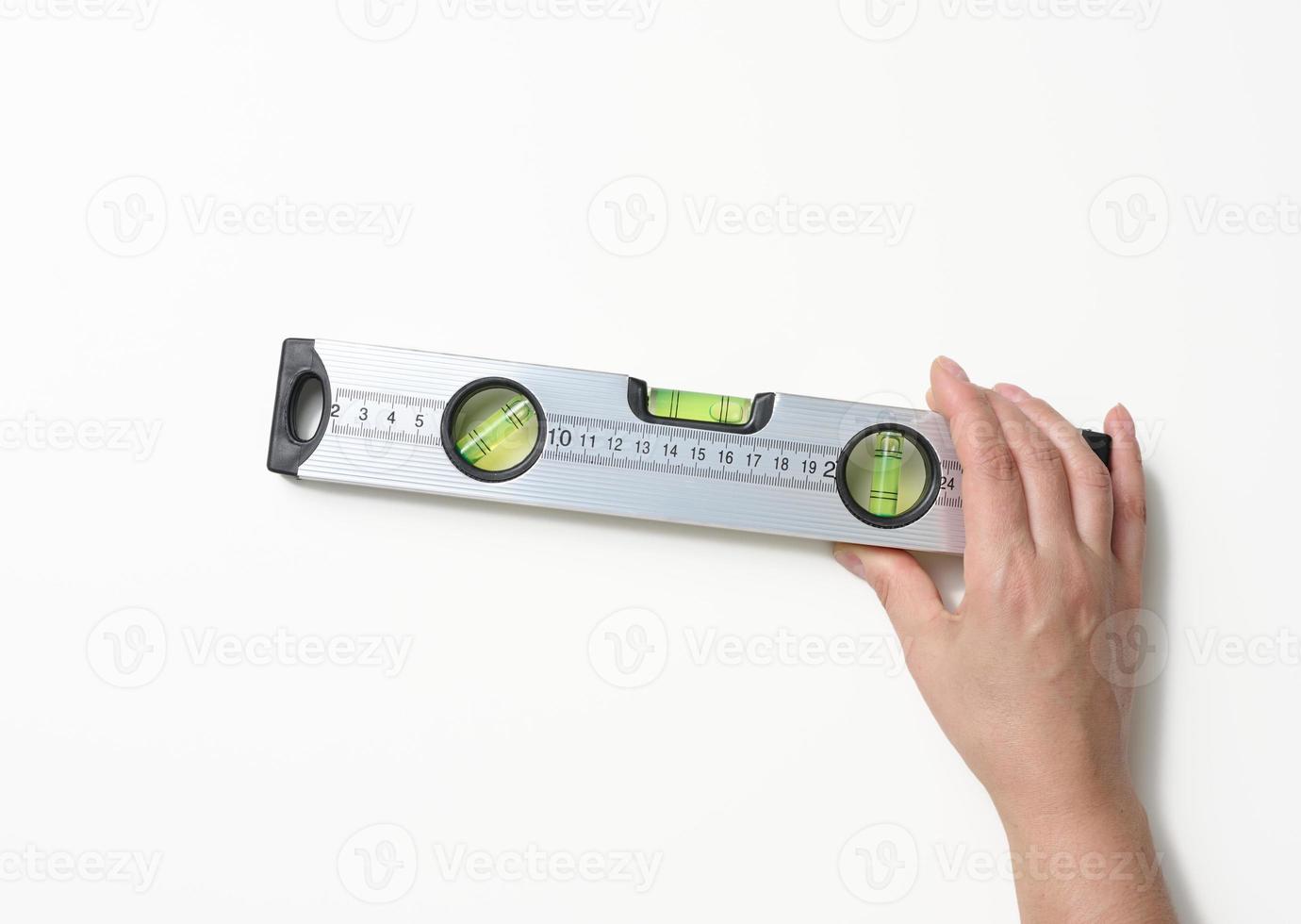 female hands holds a gray metallic building level on a white background. Measuring instrument photo