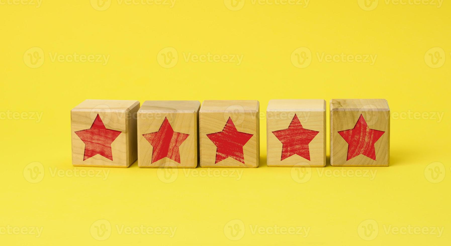 five wooden cubes with a red star on a yellow background. Quality assessment concept, rating. Best service and high business valuation photo