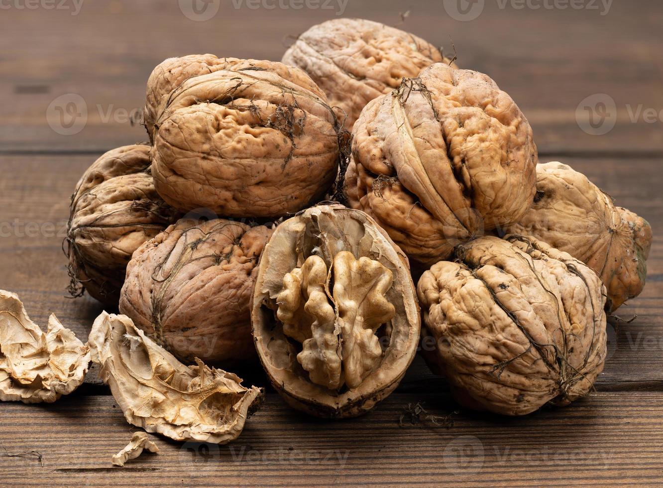 montón de nueces con cáscara en una mesa de madera marrón, cosecha de otoño foto