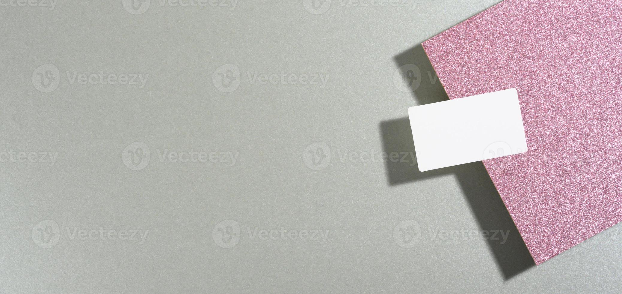 la tarjeta de presentación rectangular en blanco se encuentra sobre un moderno fondo gris hojas de papel con una sombra foto