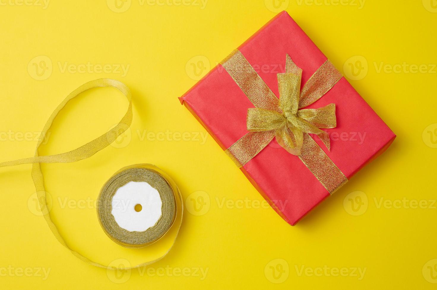 wrapped boxes in gift red paper and silk ribbon on a yellow background, top view. Congratulations and surprise photo
