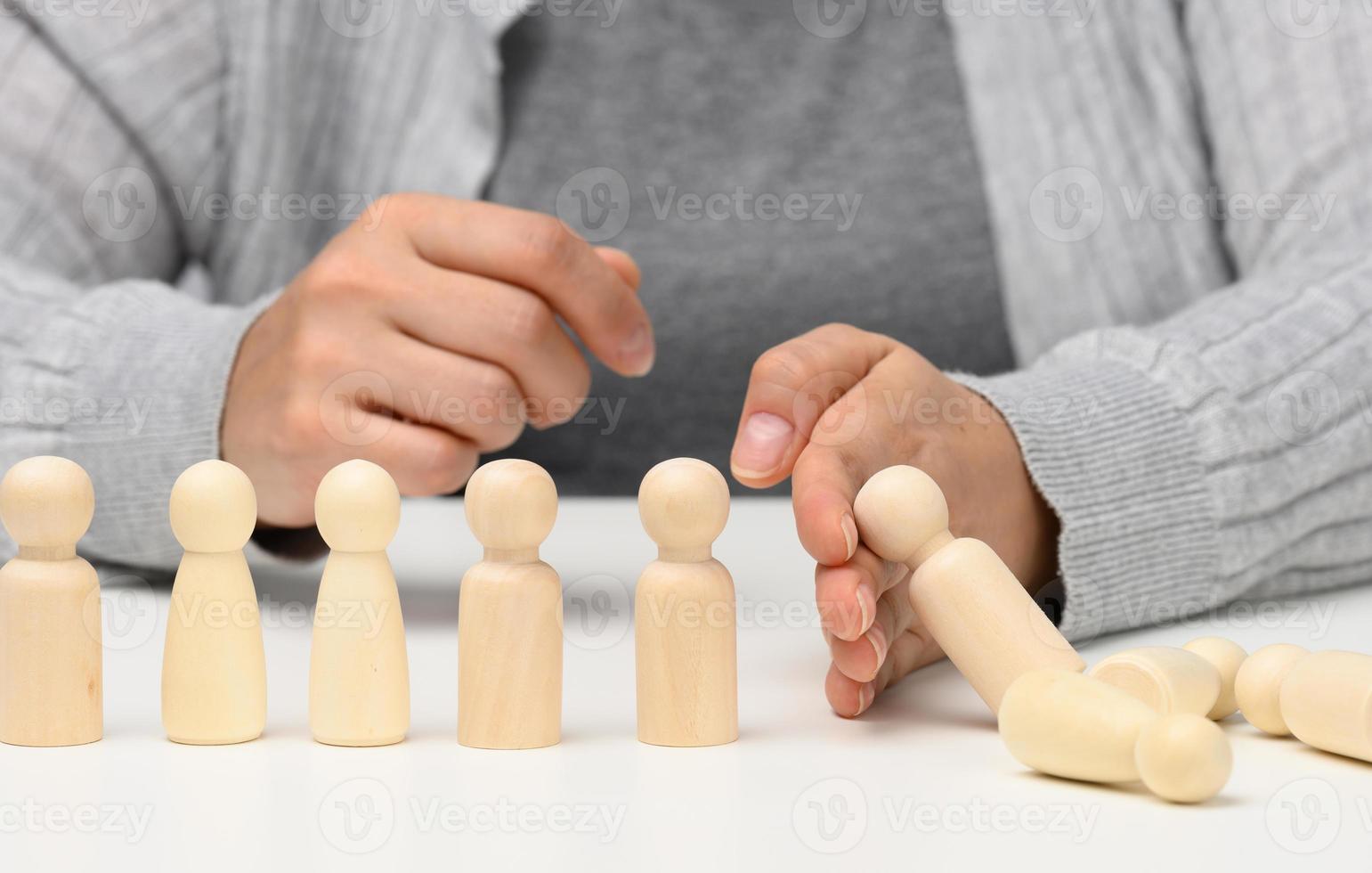 hand stops the fall of figurines of men on a white background. Concept of a strong and courageous personality capable of withstanding unequal difficulties. Strong business, photo