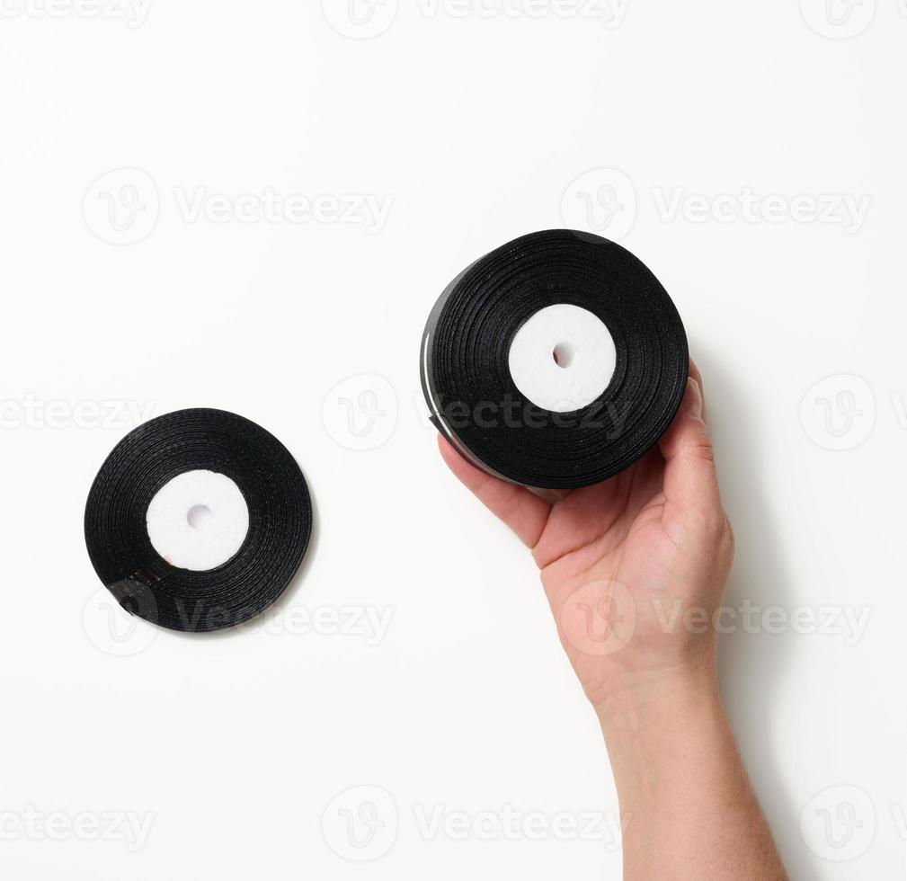 female hand holding rolled up black silk ribbon on white background photo
