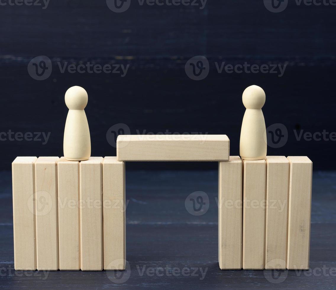 wooden figures of men on a bridge made of blocks. The concept of a dispute between opponents, dialogue photo