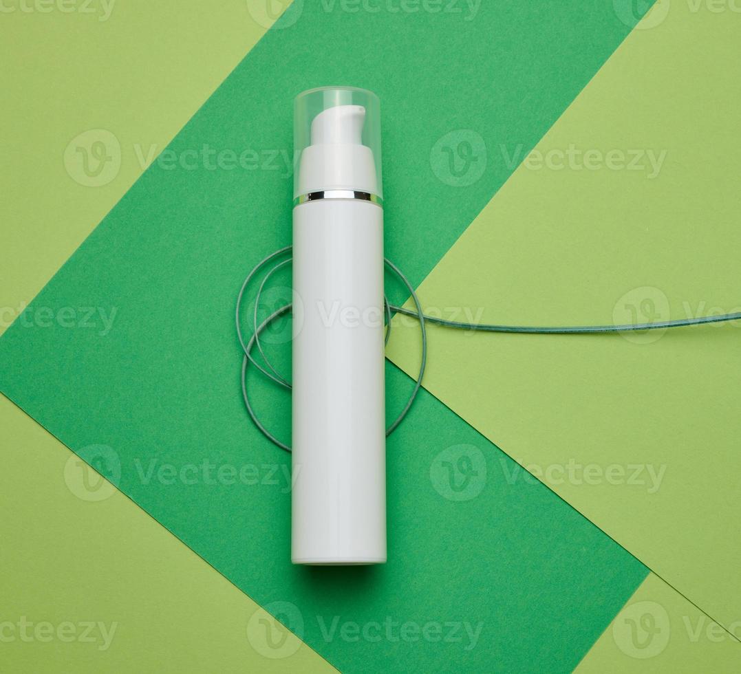 empty white plastic bottle on a green background. Cosmetic products for branding gel, cream, lotion, shampoo photo