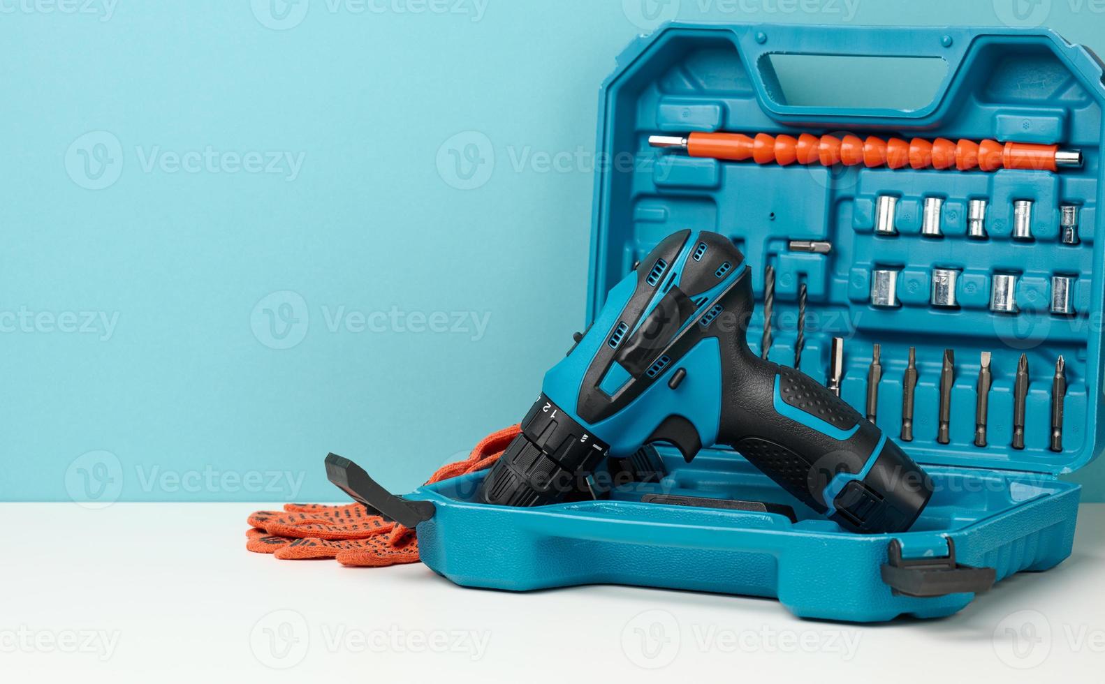 plastic box with cordless drill and set of drills and screwdrivers on white background photo