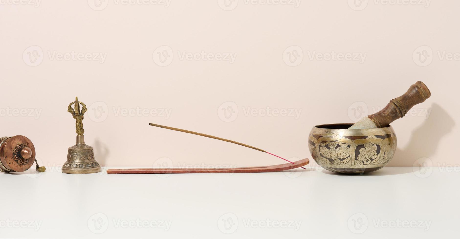 copper singing bowl and wooden clapper on a white table. Musical instrument for meditation, relaxation, various medical practices related to biorhythms, normalization of mental health photo