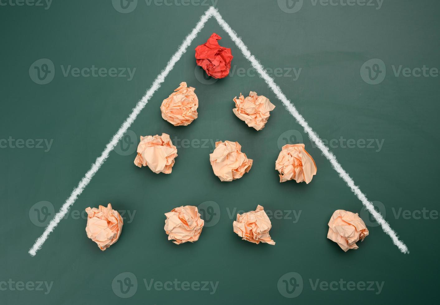 crumpled balls of paper are lined up in a wedge, moving forward photo