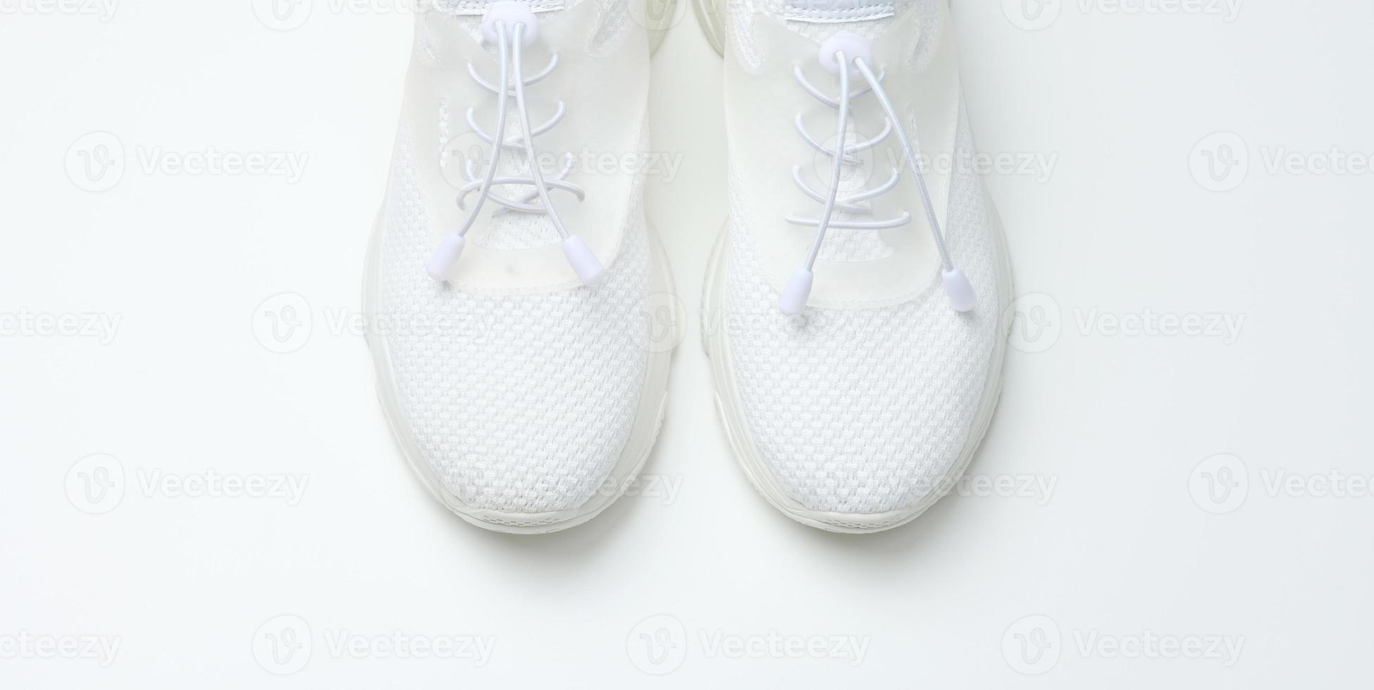 White textile sneakers on a white background, top view photo