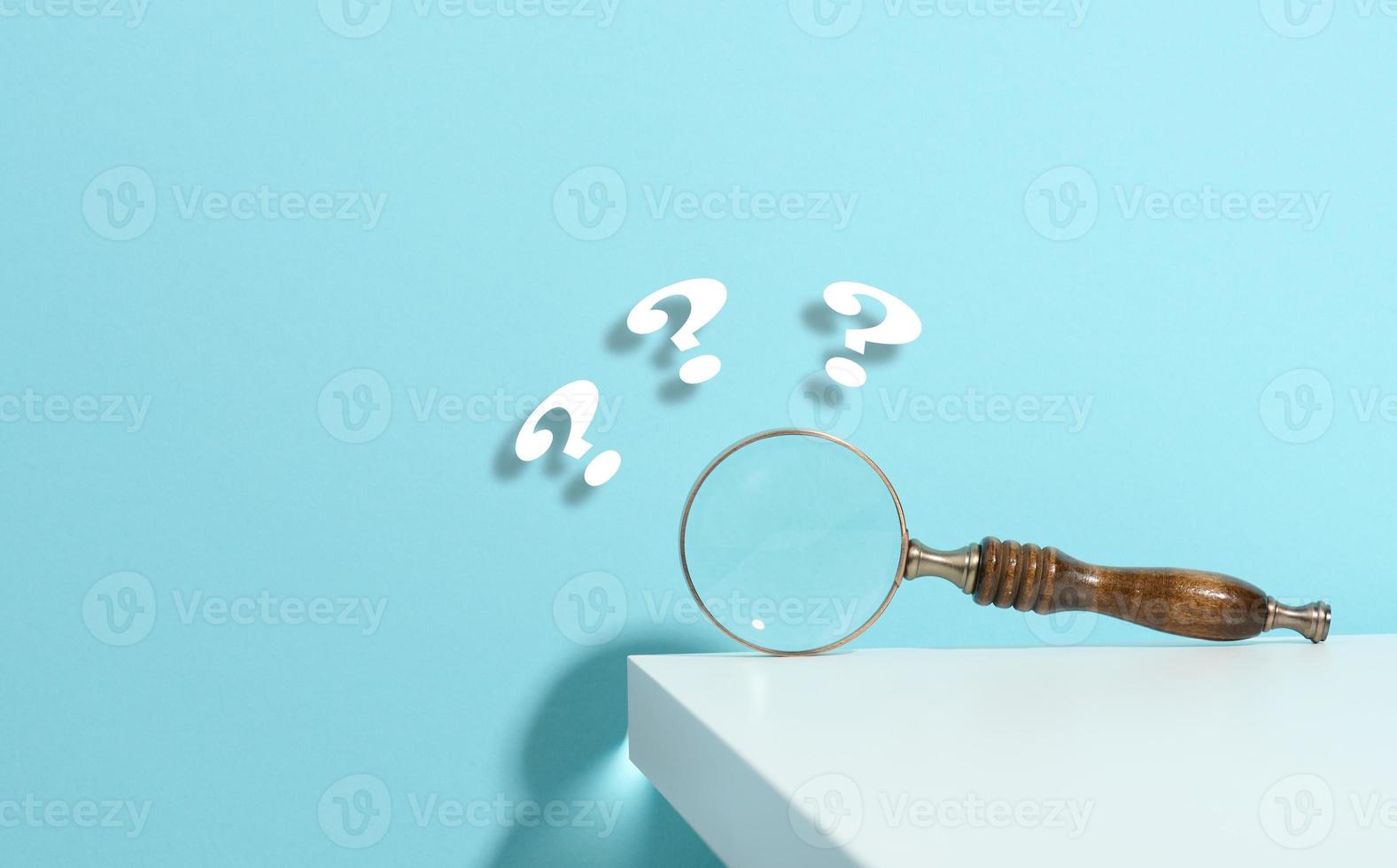 wooden magnifying glass and question marks on a blue background. The concept of finding an answer to questions, truth and uncertainty. photo