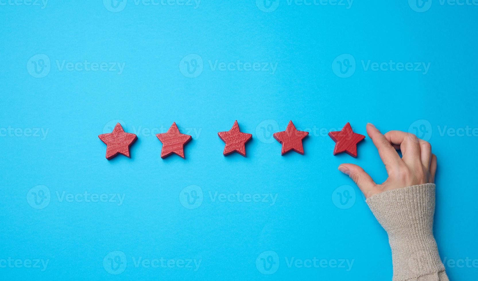 Five red stars and a hand on a blue background. Evaluation of the quality of services photo