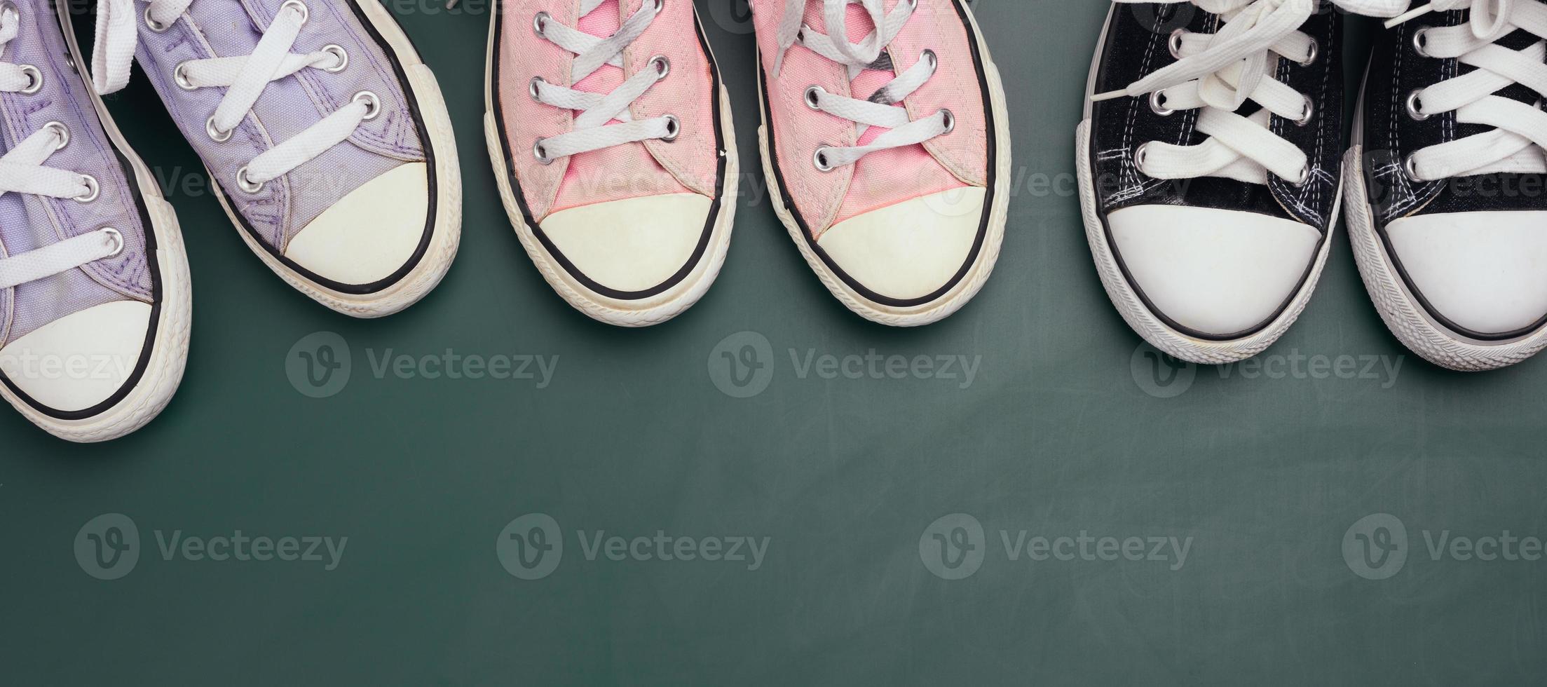 a lot of used textile sneakers on a green background, various sizes. Family concept photo