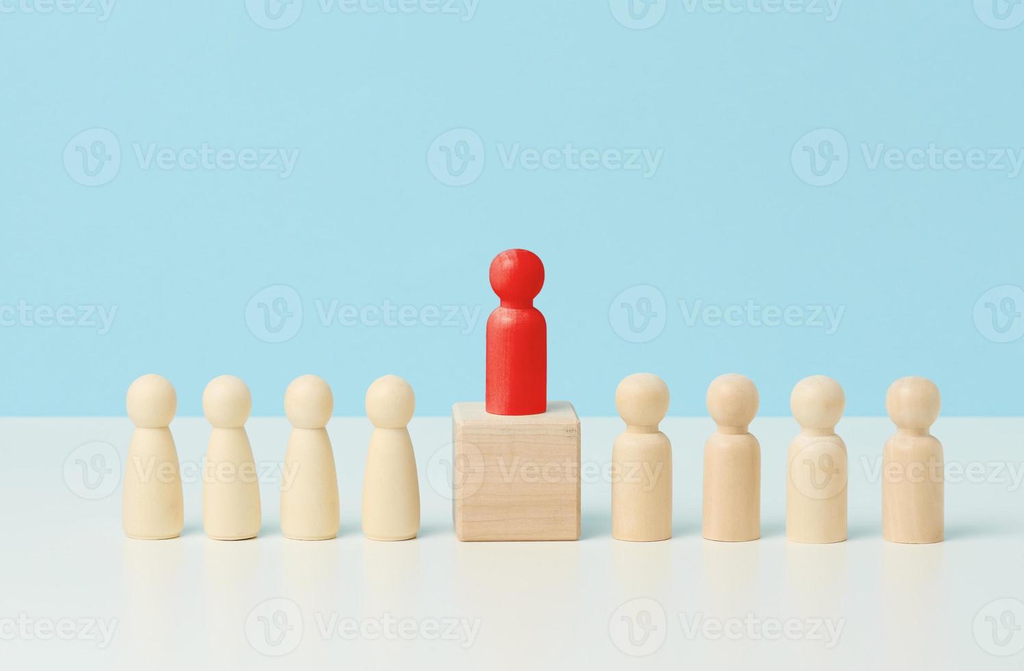 hombrecitos de madera sobre una mesa blanca, soportes rojos sobre un cubo de madera. búsqueda de empleados talentosos, reunión, manipulación de las masas, selección de empleados para el equipo foto