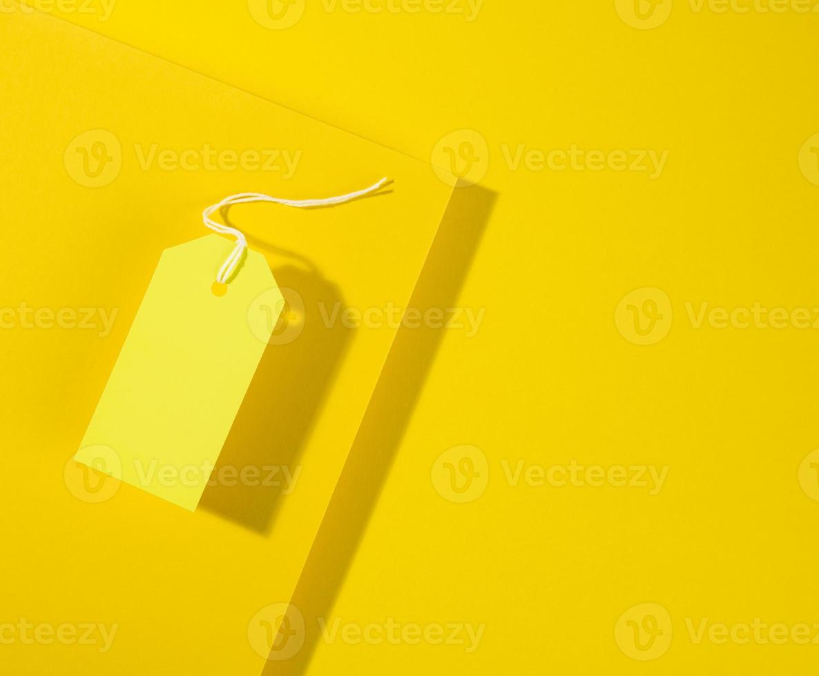 blank rectangular paper yellow price tag with white rope on yellow background photo