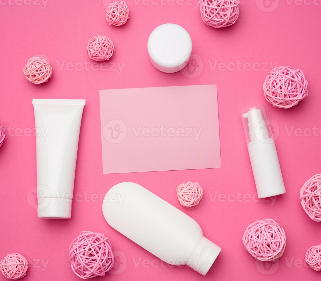 tarjeta y botella de papel vacías y tubos de plástico blancos vacíos para cosméticos sobre un fondo rosa. envases para crema, gel, suero, publicidad y promoción de productos foto