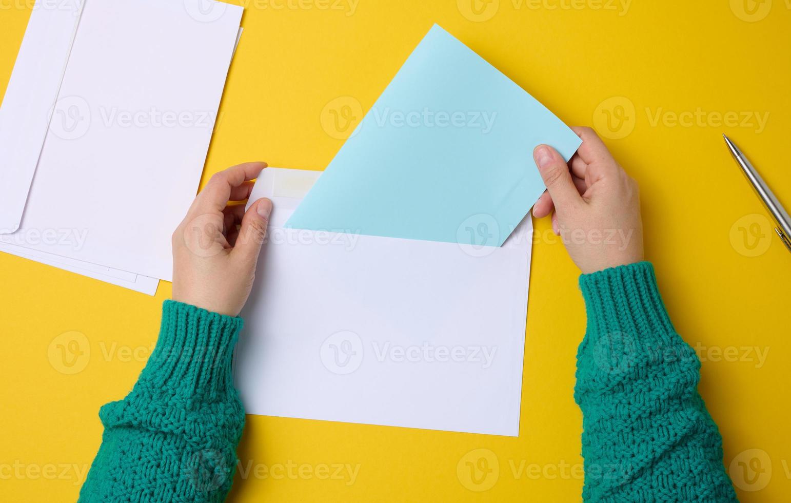 female hand holds white paper envelopes on an orange background, top view. Sending and receiving correspondence photo