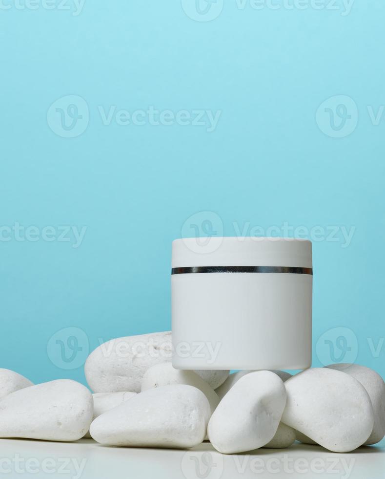 White round plastic jar for cosmetic products on a blue background. photo