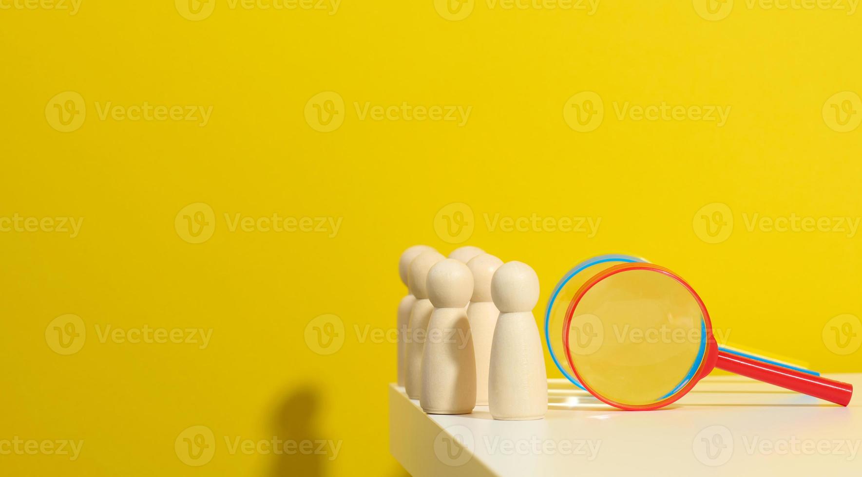 figurines of men on a white table and magnifying glass. Concept of searching for employees in the company, recruiting personnel, identifying talented and strong personaliti photo