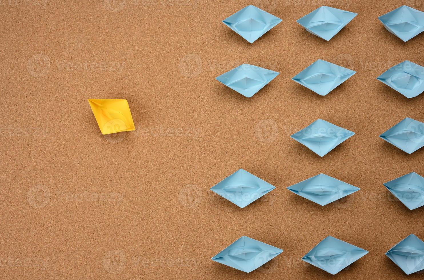 group of paper boats on a brown background. concept of a strong leader in a team, manipulation of the masses photo
