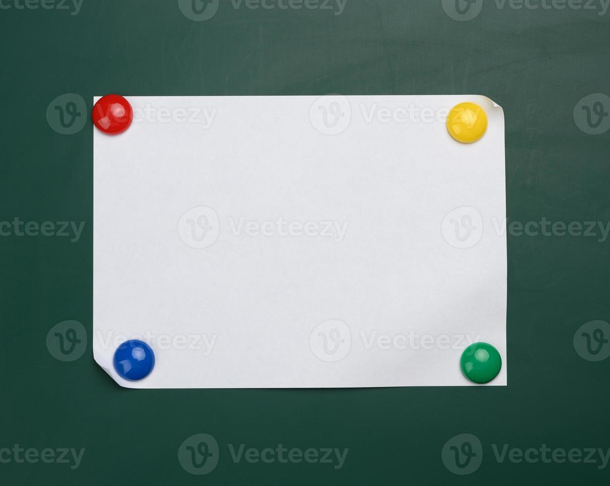 blank white sheet of a4 paper hanging on a green magnetic board. photo