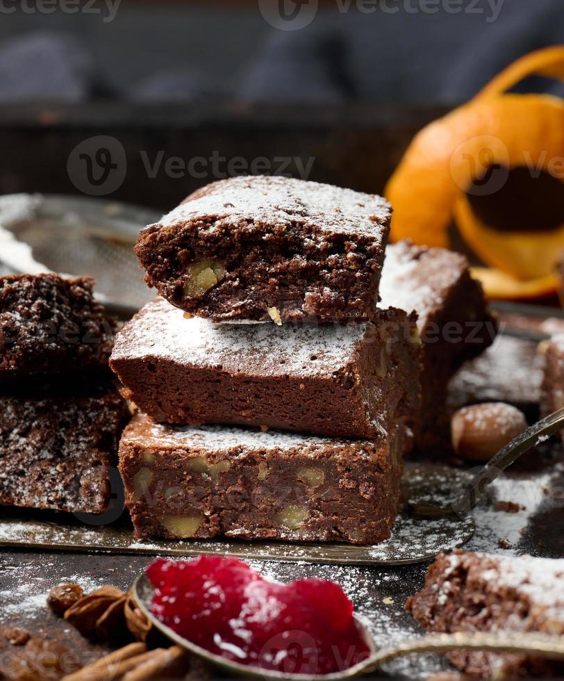 baked square pieces of chocolate brownie sprinkled with powdered sugar on the table photo