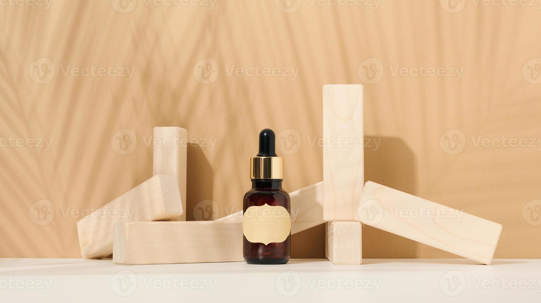 botella de vidrio marrón con una pipeta y una etiqueta marrón sobre un fondo marrón. contenedor para cosméticos, suero y aceite. sombra de hoja de palma foto