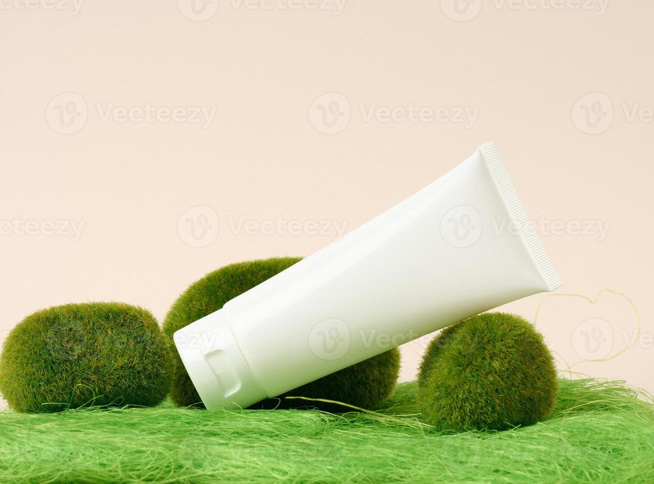 empty white plastic tubes for cosmetics on a green background. Packaging for cream, gel, serum, advertising and product promotion photo