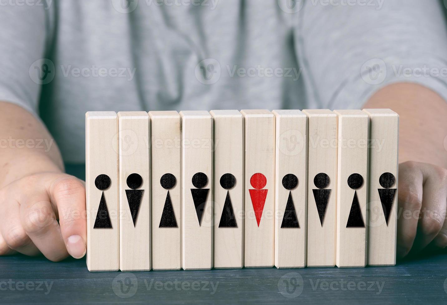 two female hands hold wooden cubes with little men on a blue table. Team care concept, leader choice, team cohesion photo