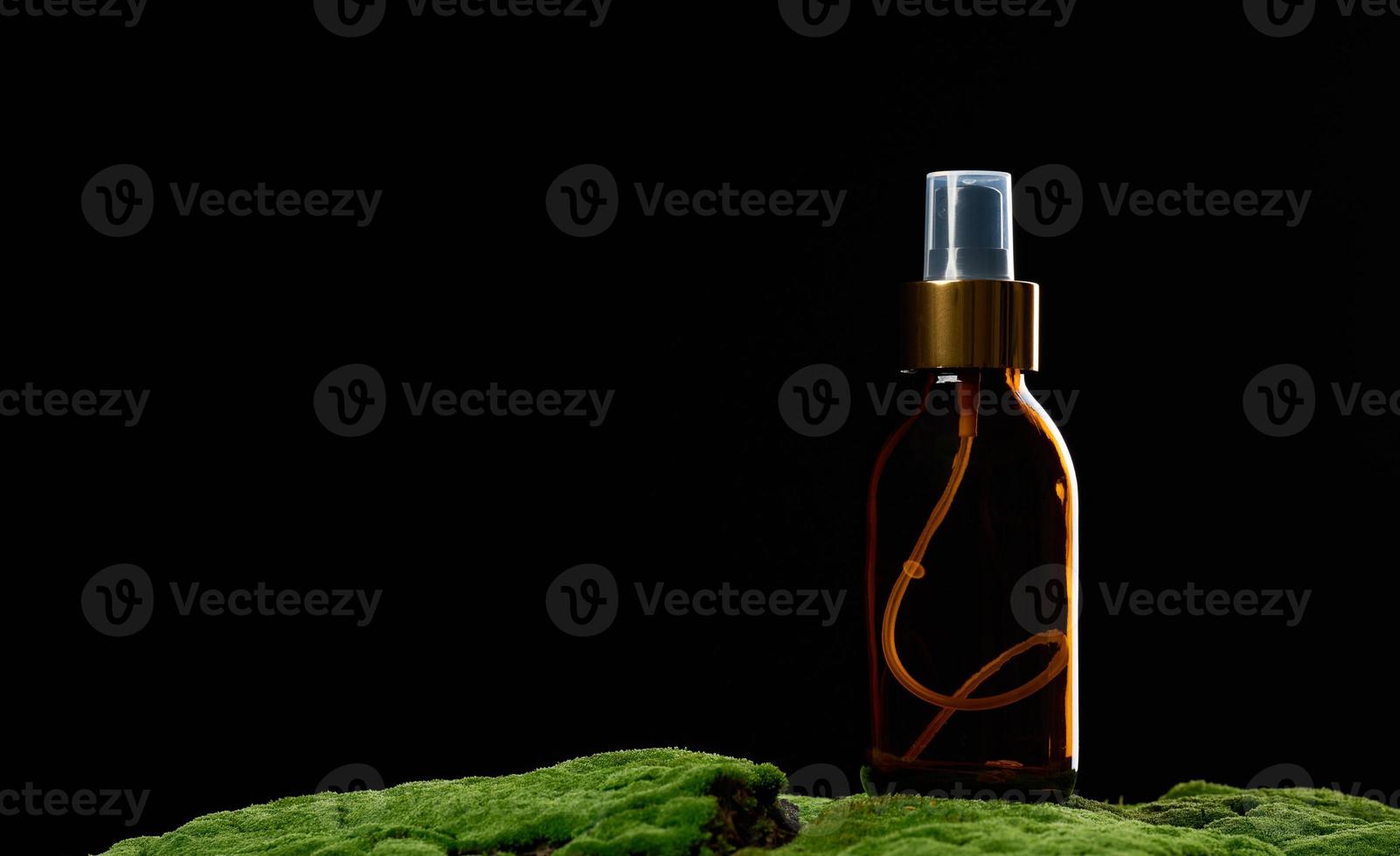 brown glass spray bottle stands on green moss photo