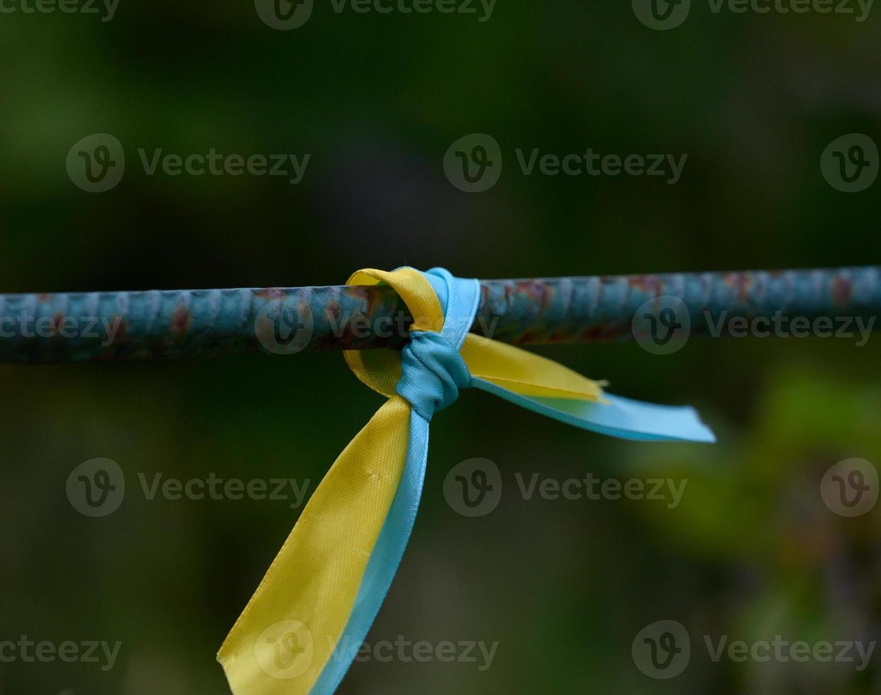 cinta de seda azul y amarilla atada a un tubo de metal. símbolo de la bandera ucraniana, lucha por la independencia foto