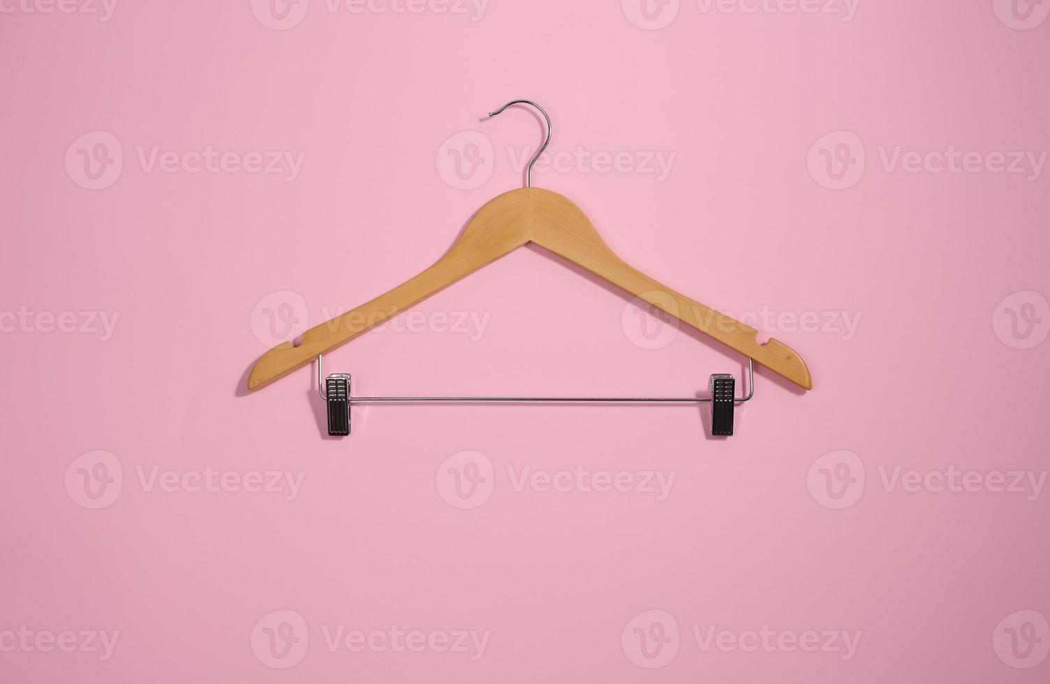 wooden hanger with metal clothespins on a pink background photo