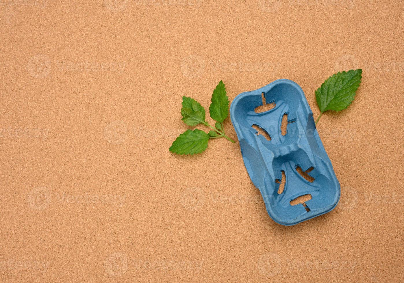 soporte de papel azul para dos vasos reciclados y hojas de menta verde sobre un fondo marrón foto