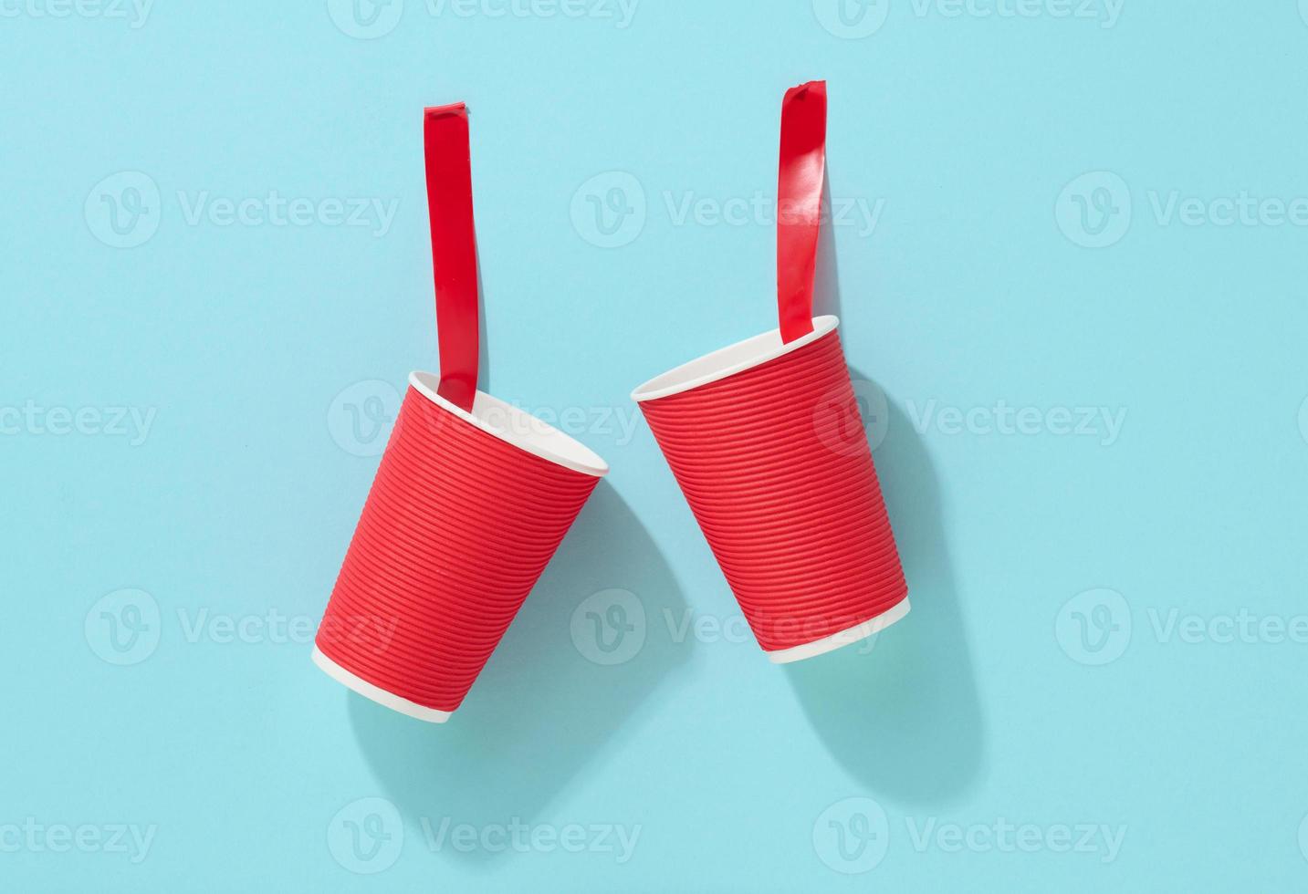 red cardboard cup glued with red sticky tape to the blue background photo